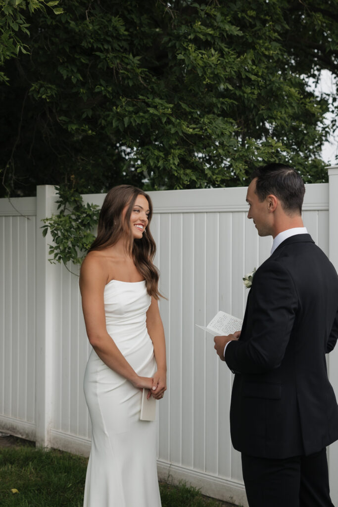 Outdoor wedding ceremony with groom reading vows to bride, documentary wedding photography in Fargo ND