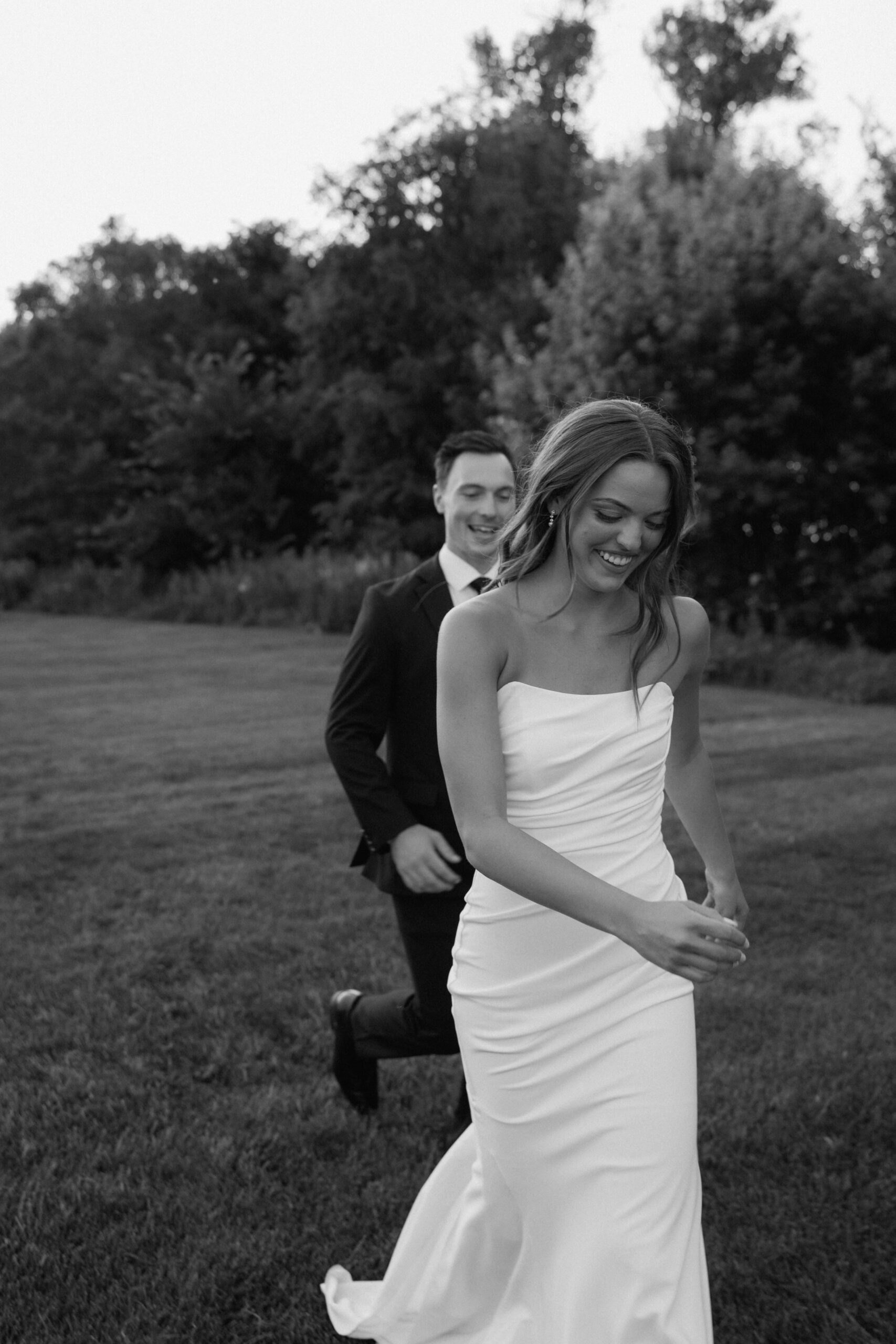 candid black and white photo of groom chasing bride during bridal portraits | Fargo nd documentary wedding
