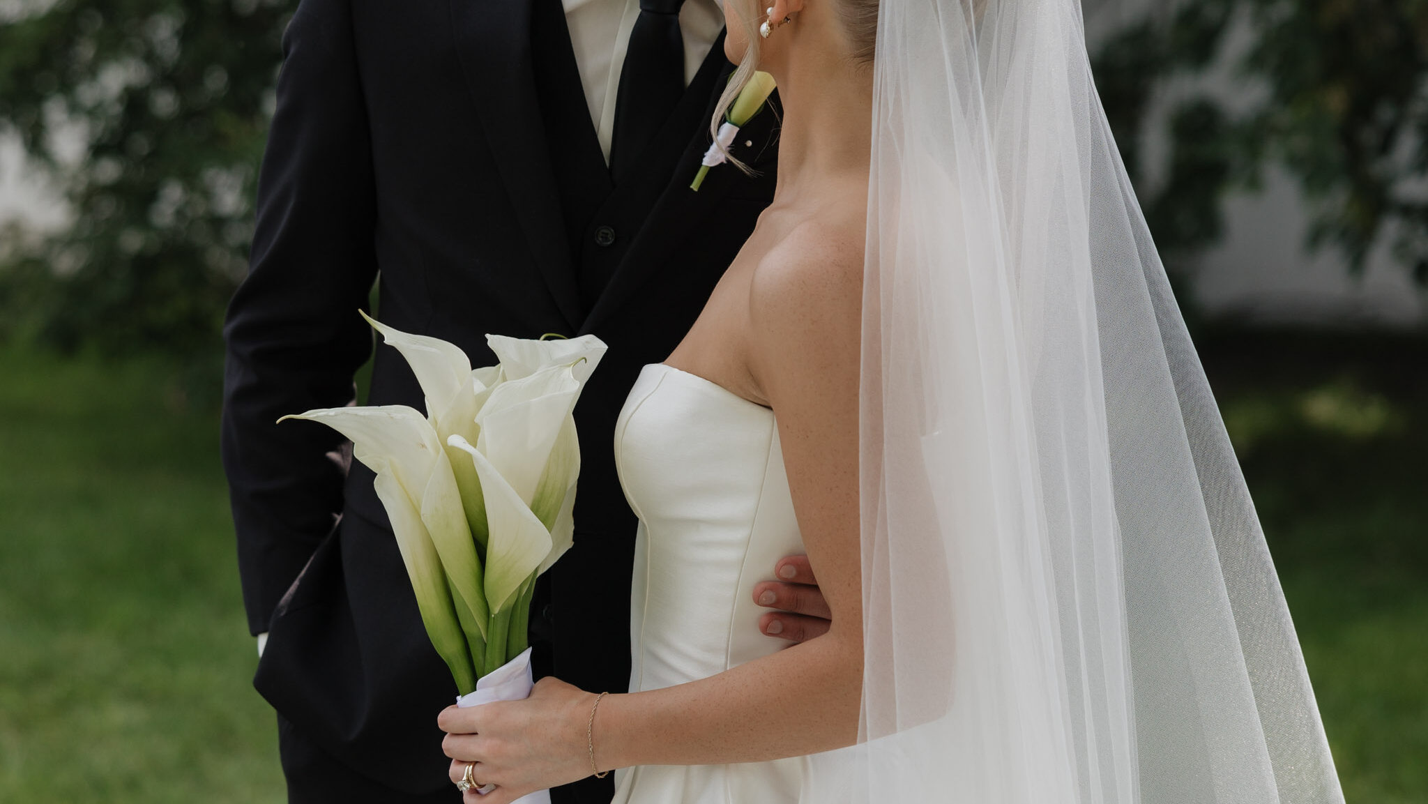 detail photo of a bride and groom facing each other focused on the flow bouquet during their portraits in Fargo North Dakota